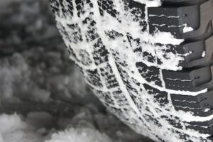 A close-up image of studless winter tire covered in snow from a road in Springfield, IL.