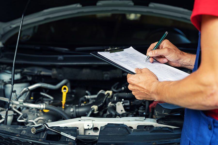 A mechanic in Springfield, IL holding a car maintenance and service checklist to ensure the vehicle is running efficiently.