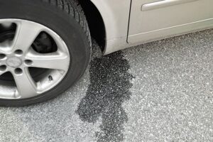 A parked vehicle in a driveway in Springfield, IL, with a clear fluid coming from the bottom of a car that is most likely water.