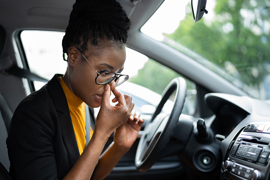 A woman wearing a black blazer and holding her nose to indicate a gas smell in her car in Springfield, IL.