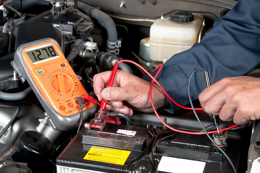 A car mechanic in Springfield, IL using a tool to check the car battery voltage.