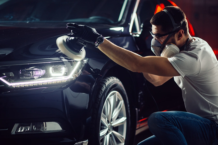 A male technician with a mask and gloves providing car detailing in a repair shop in Springfield, IL.