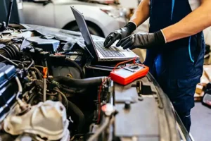Jack Stoldt Auto Service—An auto mechanic using a computer and seeking technology trends to diagnose problems with a vehicle in a garage in Springfield, IL.