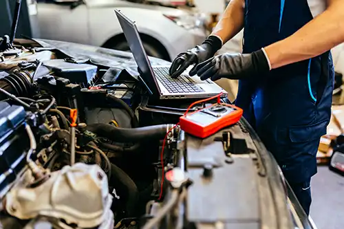 Jack Stoldt Auto Service—An auto mechanic using a computer and seeking technology trends to diagnose problems with a vehicle in a garage in Springfield, IL.