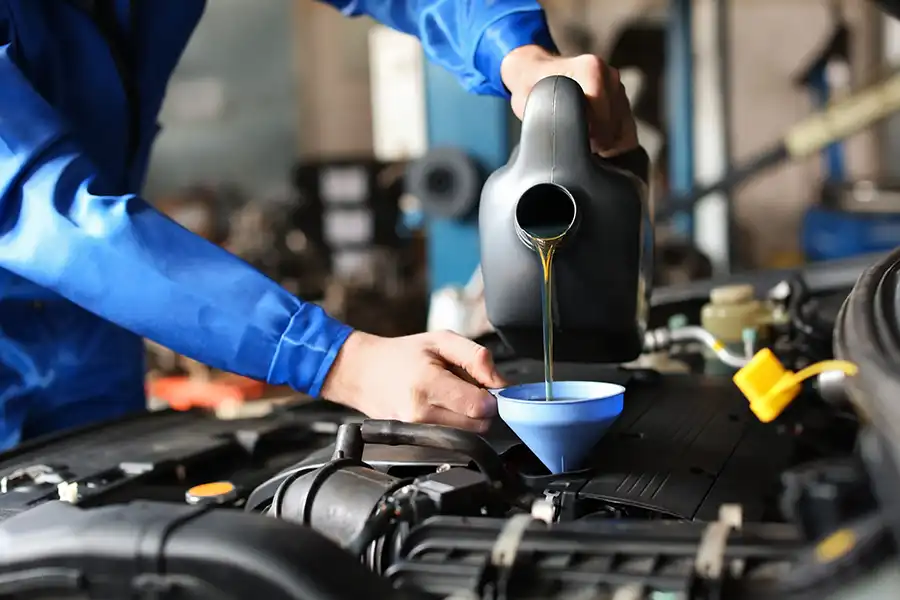 Jack Stoldt Auto Service Center—A male mechanic in a blue uniform changing the oil in a vehicle in Springfield, IL.