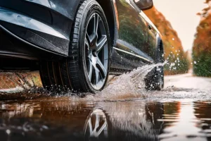 Jack Stoldt Auto Service Center — A car’s tires driving through a puddle on a wet road in Springfield, IL.