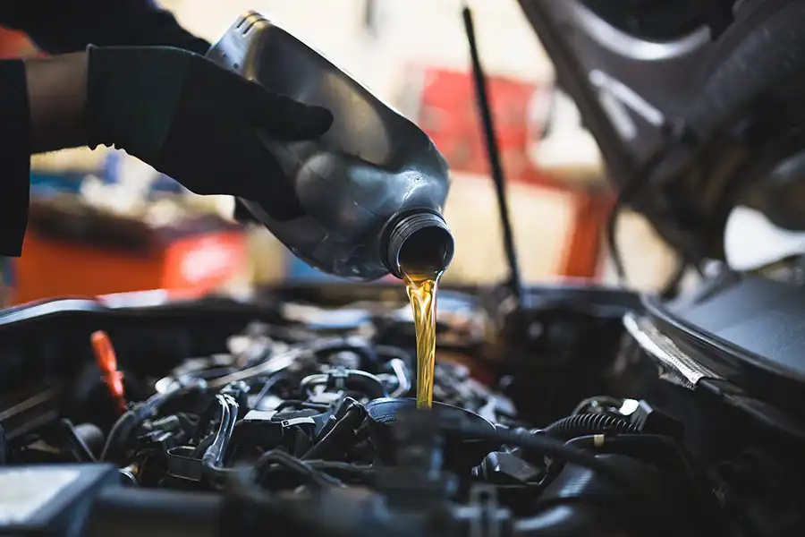 A technician at Jack Stoldt Auto Center pouring new oil into a vehicle in Springfield, IL, during an oil change service.