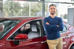Jack Stoldt Auto Service Center—A young car owner stands in front of his new car in Springfield, IL