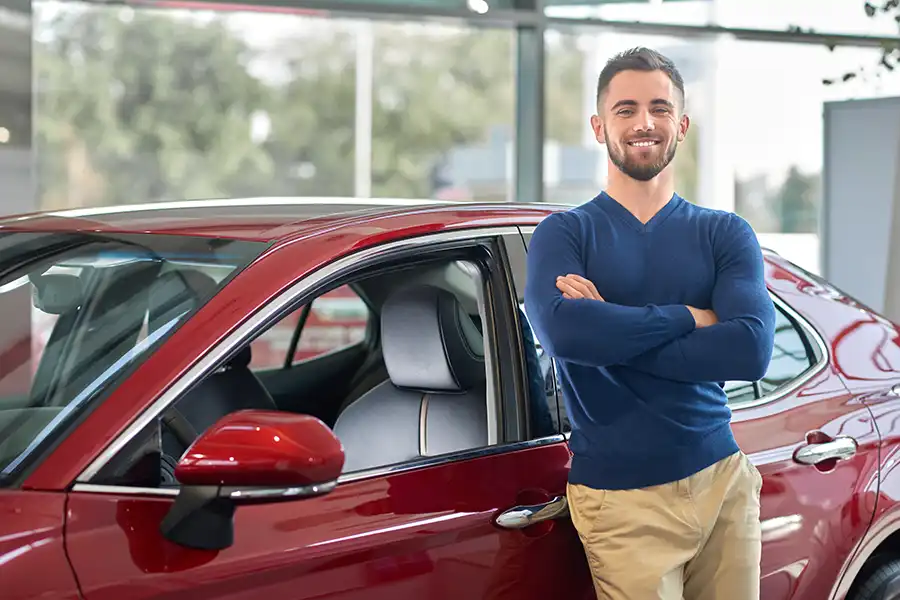 Jack Stoldt Auto Service Center—A young car owner stands in front of his new car in Springfield, IL