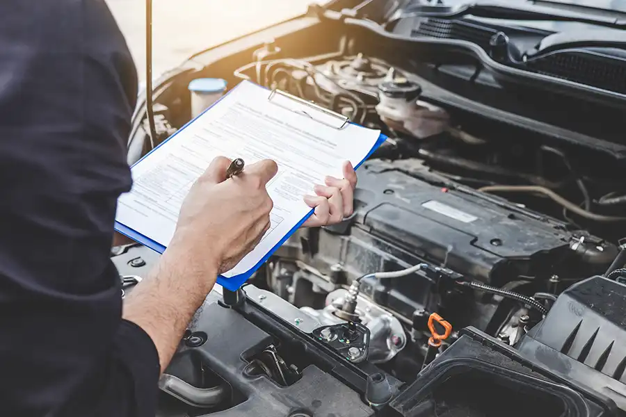 Mechanic at Jack Stoldt Auto Service Center in Springfield, IL, inspecting a vehicle during maintenance service while holding a clipboard and pen.