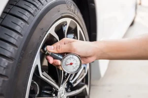 Auto technician measuring tire pressure during vehicle maintenance in Springfield, IL.